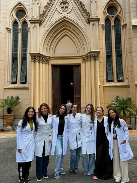 Izabelle com estudantes de jaleco em frente à capela da Santa Casa