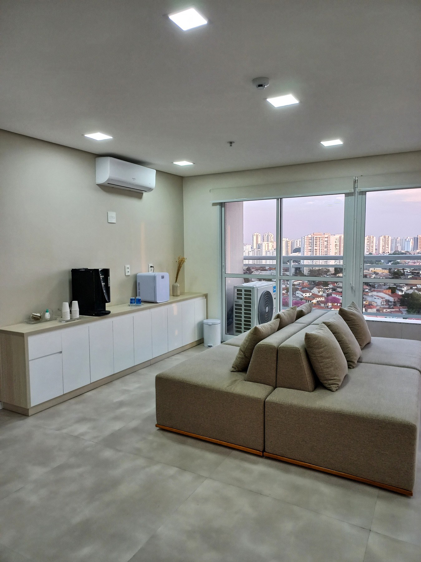 Sala de espera ampla com sofás e janelas com vista da cidade